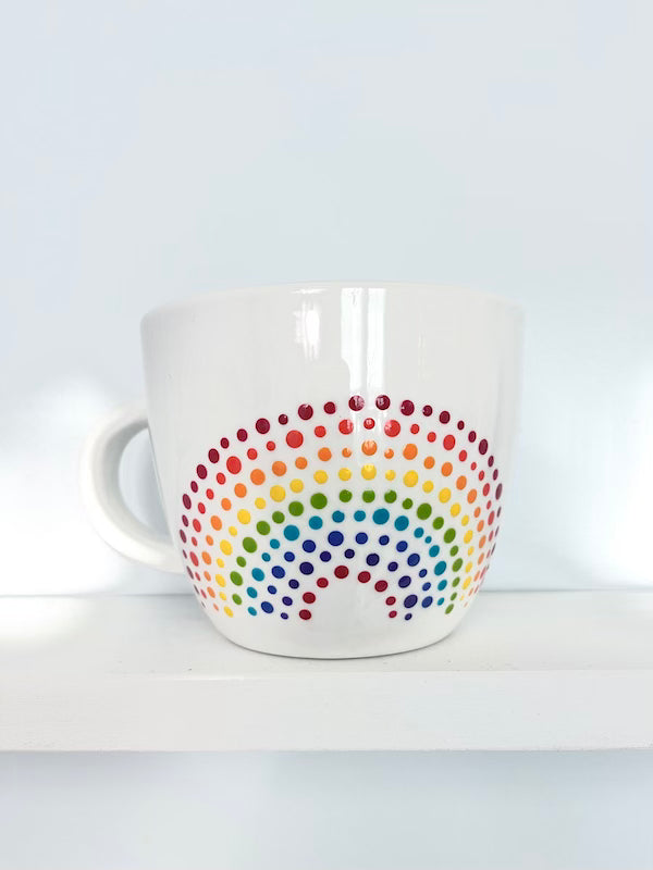 Porcelain Colorful Short Latte Mug with hand-painted dotted ROYGBIV rainbow sitting on white shelf, made by Camille Gerrick
