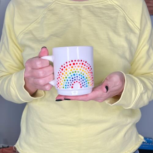Person holding Vintage-style Rainbow Dot textured Teacup in front of them. Made by Camille Gerrick.